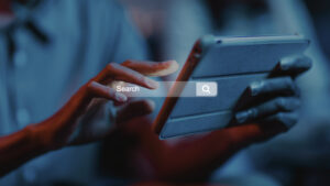 Persoon gebruikt een tablet terwijl een digitale zoekbalk zichtbaar is op het scherm